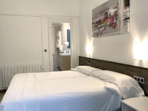 a bedroom with a large bed with white sheets at Pensión Donostiarra in Donostia-San Sebastián
