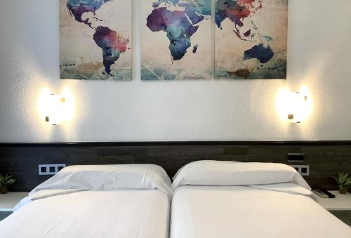 two beds in a bedroom with paintings on the wall at Pensión Donostiarra in Donostia-San Sebastián