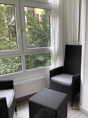 a living room with two chairs and two windows at Pensión Donostiarra in Donostia-San Sebastián