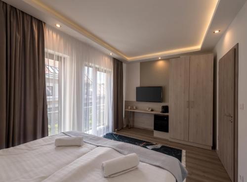 a bedroom with a bed with two white towels on it at Fibula Residence Hotel & Wellness - Adults Only in Pécs