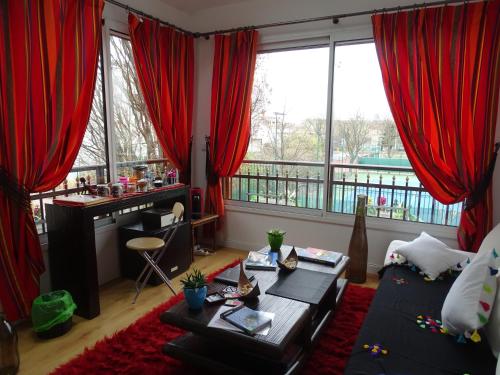 sala de estar con cortinas rojas y mesa en La bambouseraie, en Montrouge