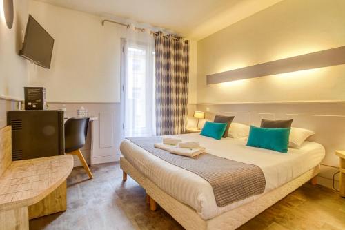 a bedroom with a large bed with blue pillows at Hôtel Saint Albert in Sarlat-la-Canéda