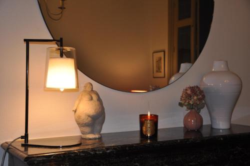a table with a lamp and a candle and a mirror at LA PETITE VERRIERE in Beaune