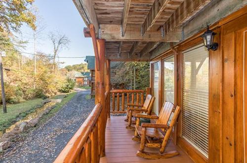a porch with rocking chairs on a wooden house at Smokey Max Cabin in Pigeon Forge