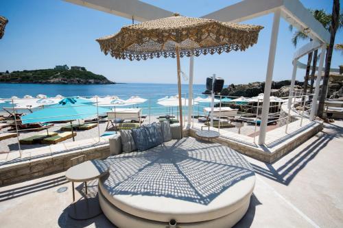 a patio with a bed and chairs and the ocean at Folie Marine Hotel & Beach Club in Jal