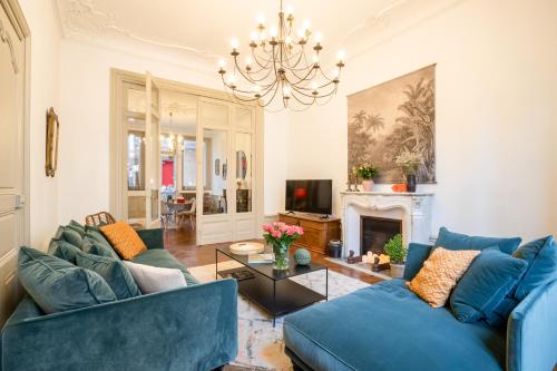 a living room with blue couches and a chandelier at LA PETITE VERRIERE in Beaune