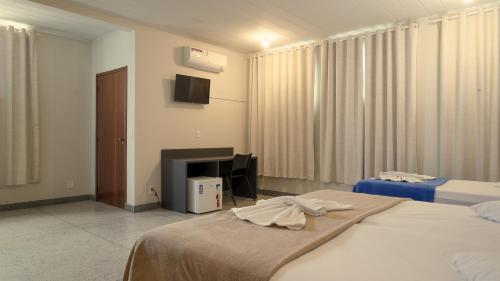 Habitación de hotel con 2 camas y TV en Hotel Araxá, en Araxá
