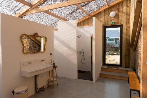 baño con lavabo, espejo y ventana en La Ferme du golf, gîte atypique et artistique, en Lancieux