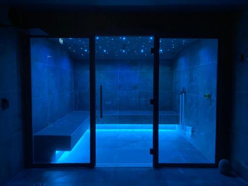 a blue room with a tub and a glass door at Hôtel 16 | 150 Montagne & Spa Nuxe in Vars