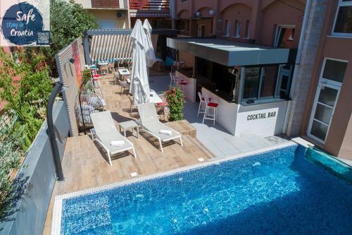 a swimming pool with chairs next to a building at Hotel Stella Maris in Vodice