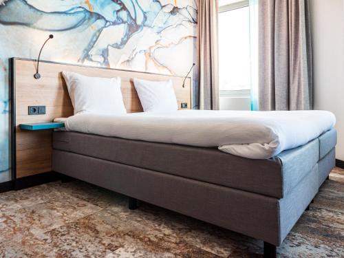 a bed in a bedroom with a painting on the wall at Fletcher Hotel-Restaurant Scheveningen in Scheveningen