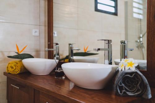 - une salle de bains avec 2 bols blancs sur un comptoir en bois dans l'établissement VILLA TAMARIN, à Ravine des Cabris