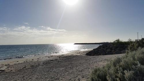 a beach with the sun shining on the water at North Coogee Beach House in Fremantle