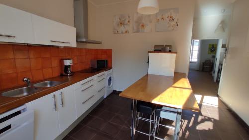 une cuisine avec des armoires blanches, un évier et un réfrigérateur dans l'établissement La Montcuquoise, à Montcuq