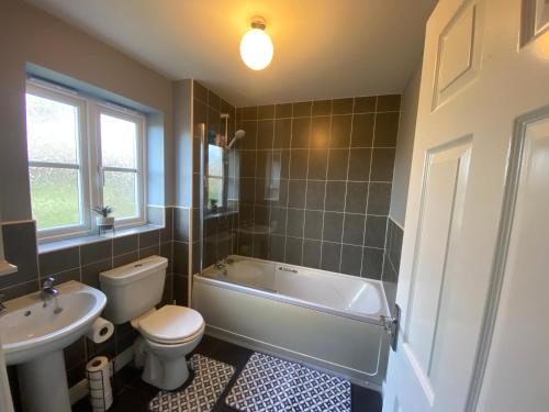 ein Badezimmer mit einer Badewanne, einem WC und einem Waschbecken in der Unterkunft Silver Stag Properties, Spacious 3 BR Haven in Ashby de la Zouch