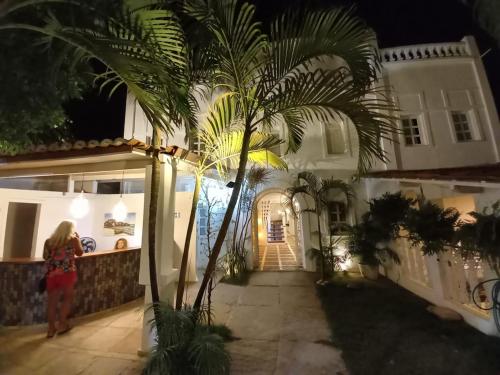 a woman standing in front of a house with a palm tree at Casarão Jeri in Jericoacoara