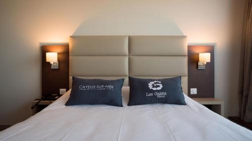 una camera con un letto con due cuscini sopra di Hotel Les Galets Bleus a Cayeux-sur-Mer