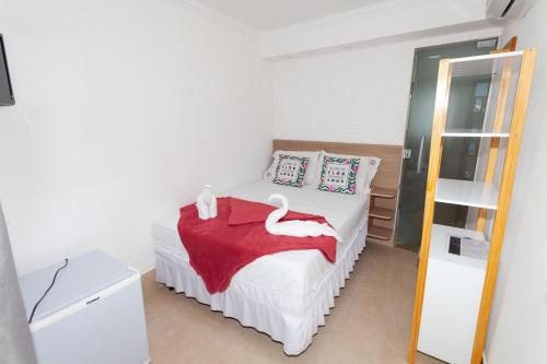 a bedroom with a white bed with a red blanket at Pousada Villa Goyá in São José da Coroa Grande