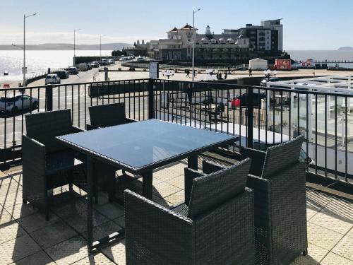 a table and chairs on a balcony with a view of the beach at Pavilion Holiday Apartments in Weston-super-Mare