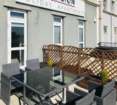 a glass table and chairs in front of a restaurant at Pavilion Holiday Apartments in Weston-super-Mare
