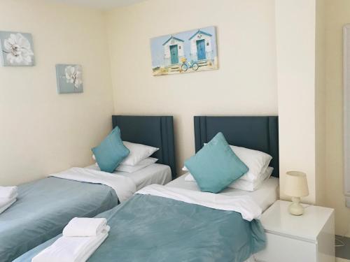 two beds with blue and white pillows in a room at Pavilion Holiday Apartments in Weston-super-Mare