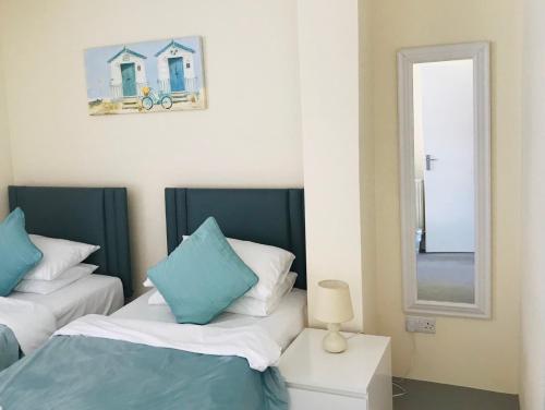 a bedroom with two beds and a mirror at Pavilion Holiday Apartments in Weston-super-Mare