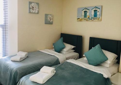 two beds in a room with green and white pillows at Pavilion Holiday Apartments in Weston-super-Mare