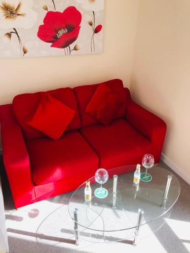 a red couch with red pillows and a glass table at Pavilion Holiday Apartments in Weston-super-Mare