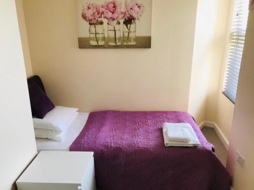 a bedroom with a bed with purple sheets and pink flowers at Pavilion Holiday Apartments in Weston-super-Mare