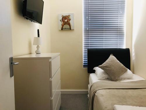 a bedroom with a bed and a dresser with a television at Pavilion Holiday Apartments in Weston-super-Mare