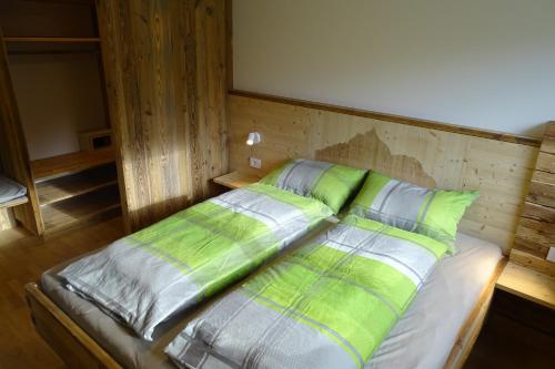 a bed with green and white pillows in a room at Schmalzlhof in Siusi