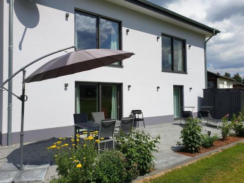 a patio with chairs and an umbrella in front of a house at Ferienhaus Dreier-Ley in Üdersdorf