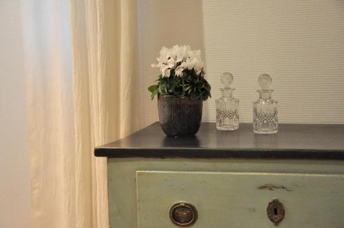 a vase with white flowers on top of a dresser at LA PETITE VERRIERE in Beaune