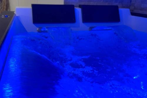 ディジョンにあるAppart&Spa Devosgeの青い水のプール(2台のモニター付)