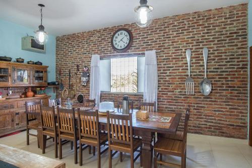 a dining room with a clock on a brick wall at Sítio Pandora - Interior de Minas por Carpediem in Pedro Leopoldo