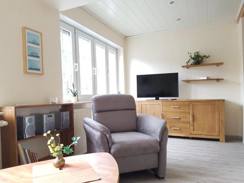 sala de estar con silla y TV de pantalla plana en Ferienwohnung Wandelt, en Essen