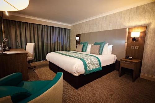 a hotel room with a large bed and a chair at Mercure Milton Keynes Hotel in Milton Keynes