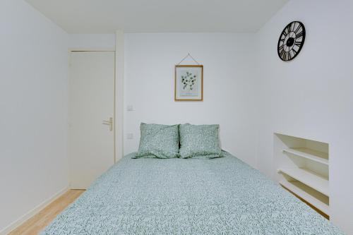 - une chambre avec un lit doté de draps bleus et d'une horloge dans l'établissement La Bridole, à Vitré