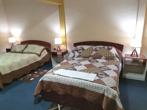 2 lits dans une chambre avec 2 lampes sur des tables dans l'établissement A&A apartamento, à Cochabamba