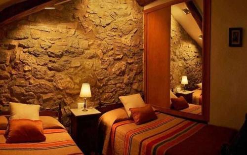 a bedroom with two beds and a stone wall at Casa Rural LEra in Torre de Fontaubella