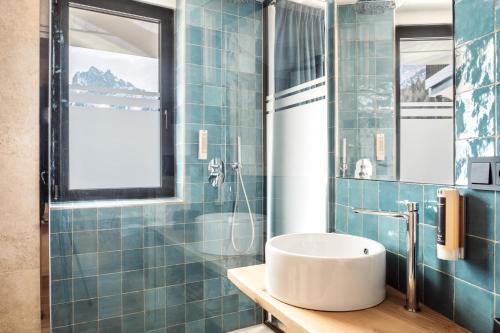 a blue tiled bathroom with a sink and a shower at Turmchalet Adults Only in Braies