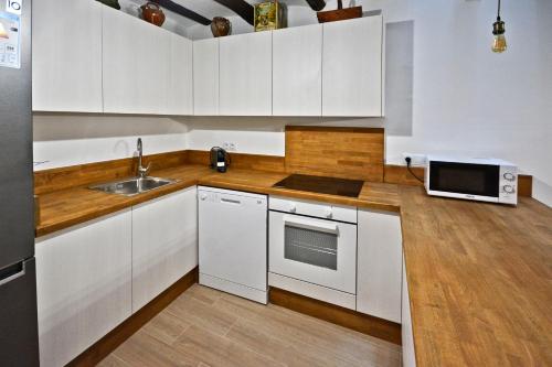 a kitchen with white cabinets and a sink and a microwave at Casa del Tio Vicente in Calaceite