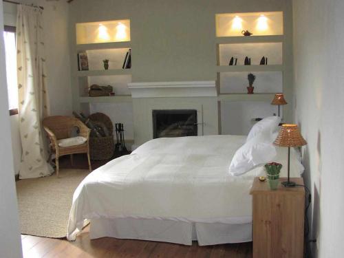- une chambre avec un lit blanc et une cheminée dans l'établissement Casa Rural La Cateta, à Mancha Real