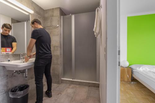 a man standing in a bathroom with a sink at Nyon Hostel in Nyon