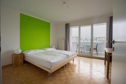 a bedroom with a green wall and a bed at Nyon Hostel in Nyon