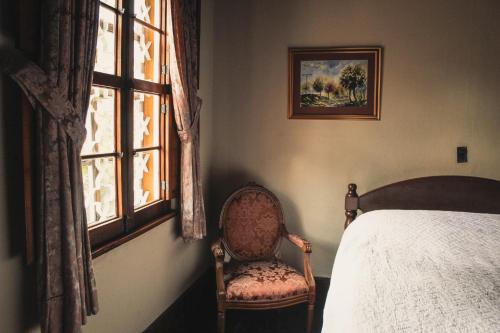 a bedroom with a bed and a chair and a window at Casa Carmel Bed & Breakfast in Guatemala