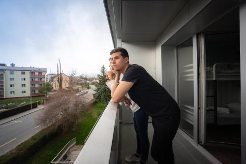 a man standing on a balcony looking out of a window at Nyon Hostel in Nyon