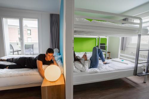 two people laying on bunk beds in a room at Nyon Hostel in Nyon