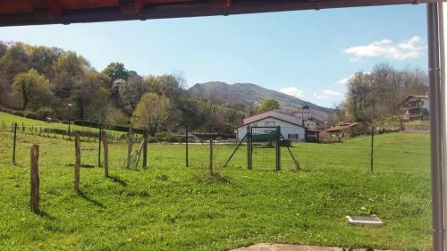 a fence in a field with a house in the background at Habitacion - dormitorio rural itaka in Zugarramurdi