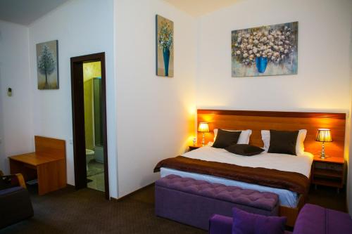 a bedroom with a large bed and a purple couch at Hotel Regal in Costinesti